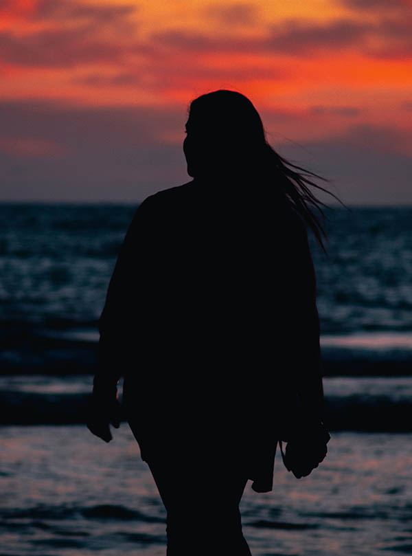 Silhouette of Middle Eastern young woman along the sea at sunset. 