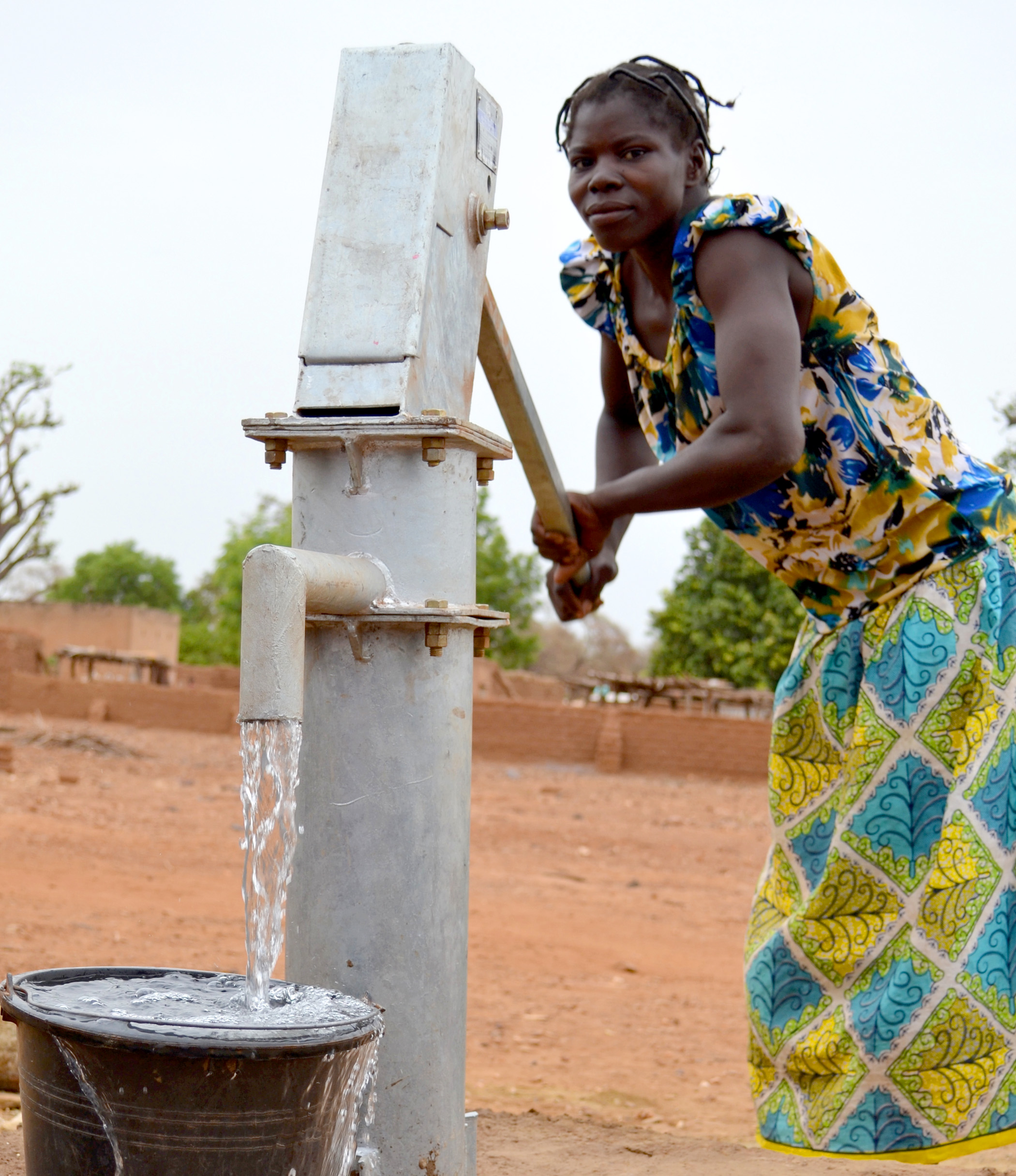 A local woman uses a pump to draw water from the new drilled borehole.