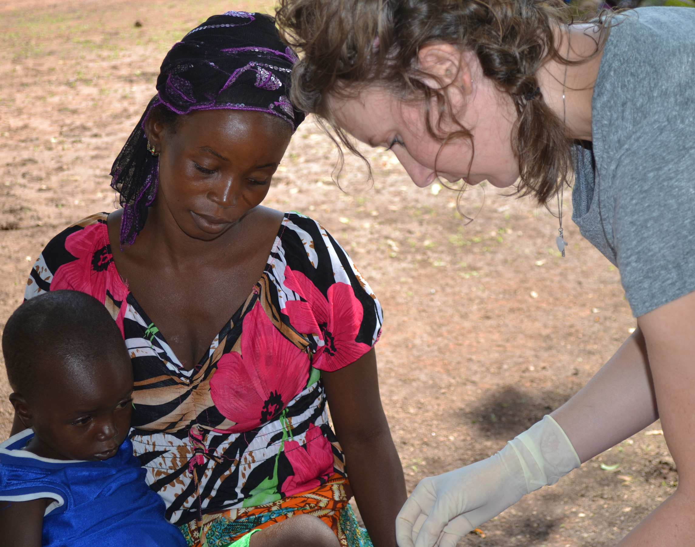 Lindsay Wiggers, another former intern, checks the health of a young child while the mother looks on.