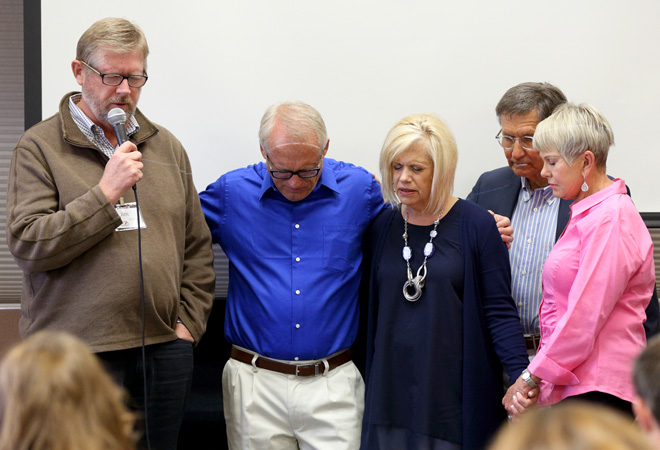 Jim Gordon, chairman of the Reach Beyond board of trustees, prays for the Harlings along with Wayne and Willi Pederson.