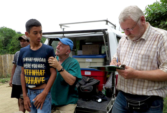 Dr. Steve Nelson examines a quake survivor while Hermann Schirmacher takes notes.