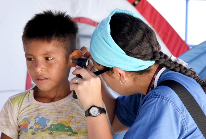 An Ecuadorian physician, Dr. Katalina Rosero, checks the ears of a young patient.