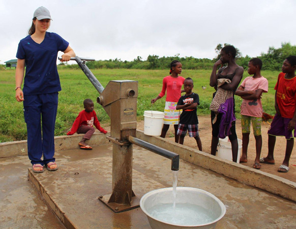 An intern draws water from a water pump in Hateka, a village outside of Accra where Reach Beyond helped install a clean water well in 2009. This resulted in much-improved health in the community.