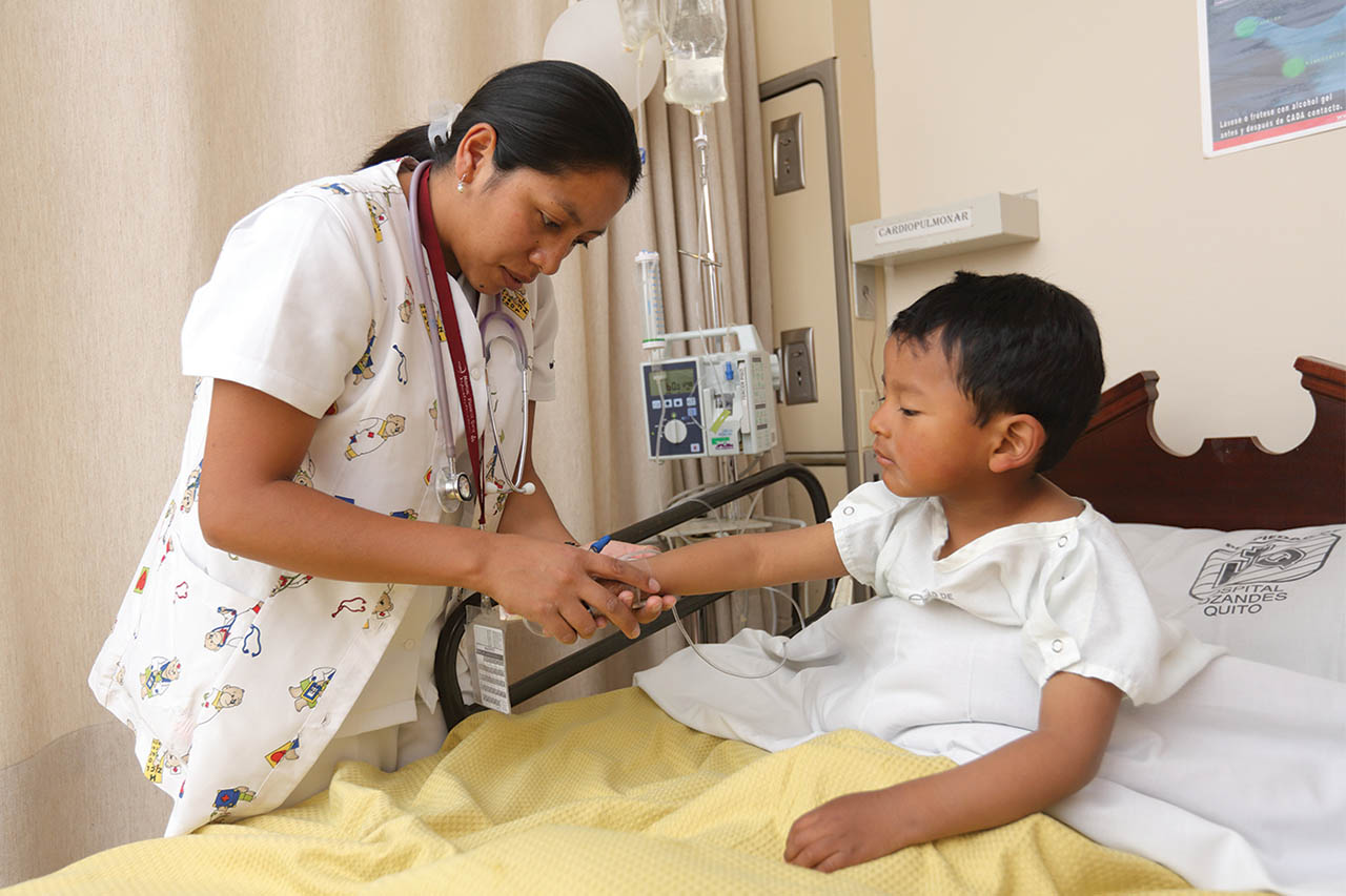 A nurse check the IV of a child patient at Hospital Vozandes Quito