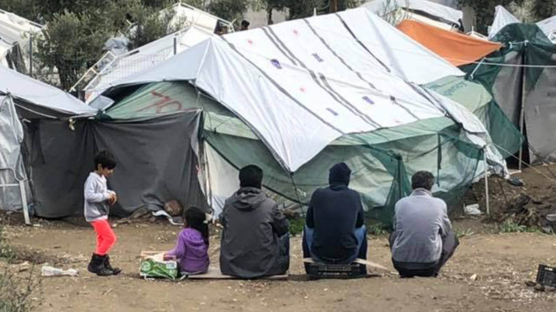 Refugees sit and talk in the Moria refugee camp in Greces