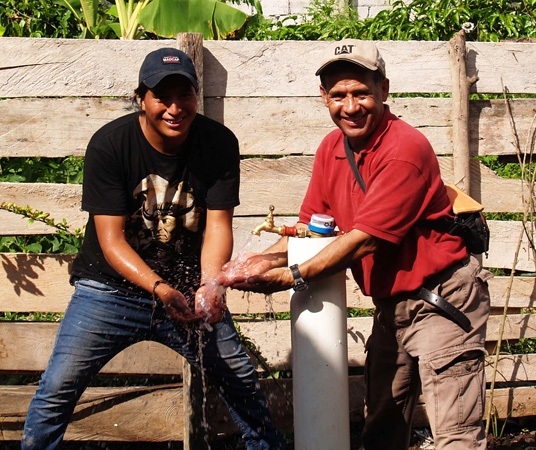 Reach Beyond's César Cortez (right) with a local resident in Yalare check out one of the community's new faucets.