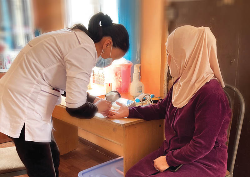 A nurse checks the vital signs of a woman in a rural village