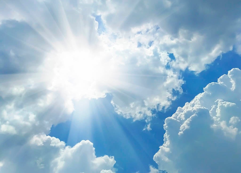 Sun shining brightly through the clouds with sunbeams
