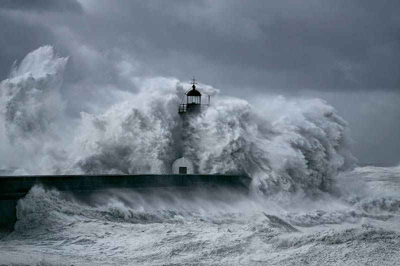 A storm with high waves batters a lighthouse