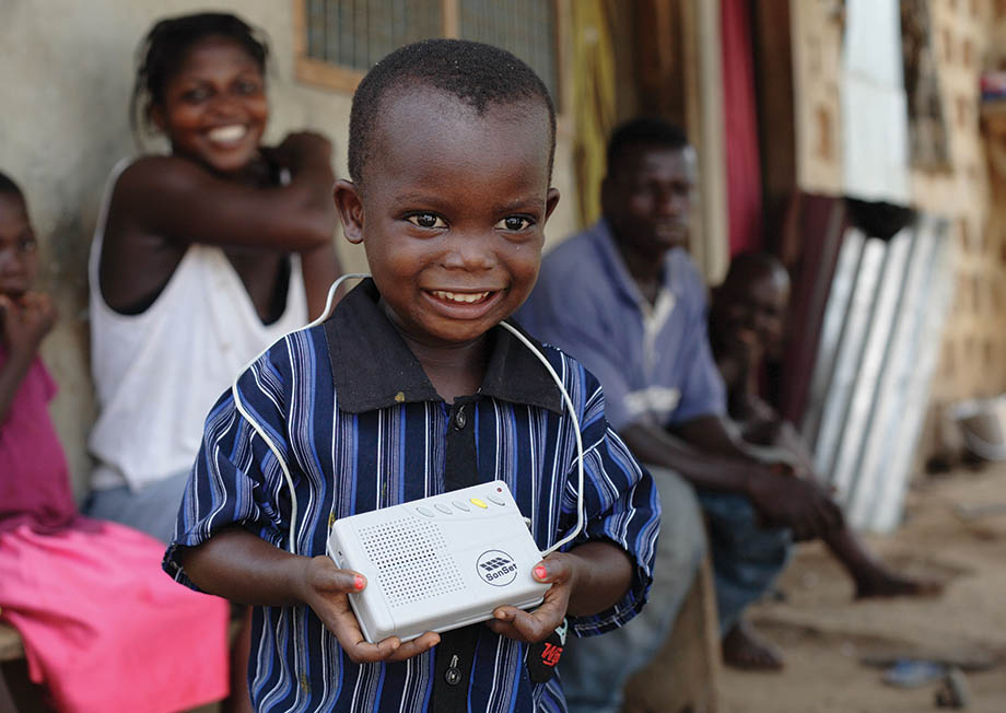 Boy holding a solar-powered Sonset radio in a rural village of Ghana