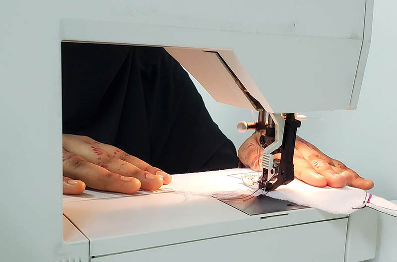 Closeup of the hands of a woman learning to use a sewing machine