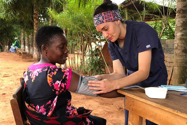 A summer intern takes blood pressure during a mobile medical caravan in Ghana