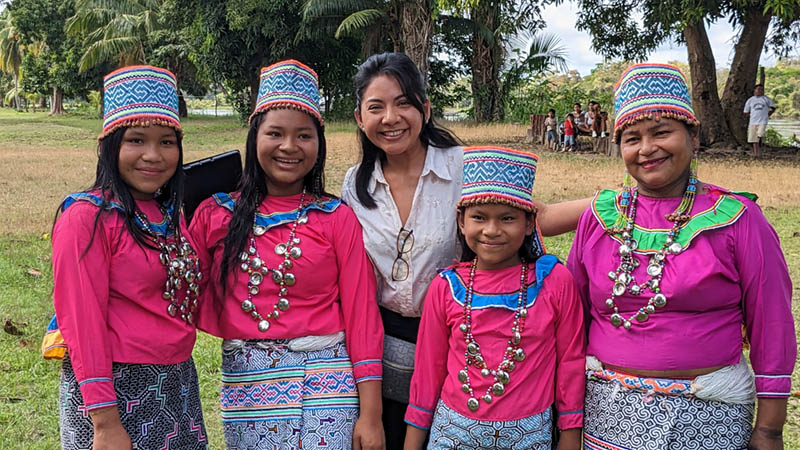 One of the team poses with Peruvian people who live along the Ucayali River who are dressed in colorful traditional clothing.