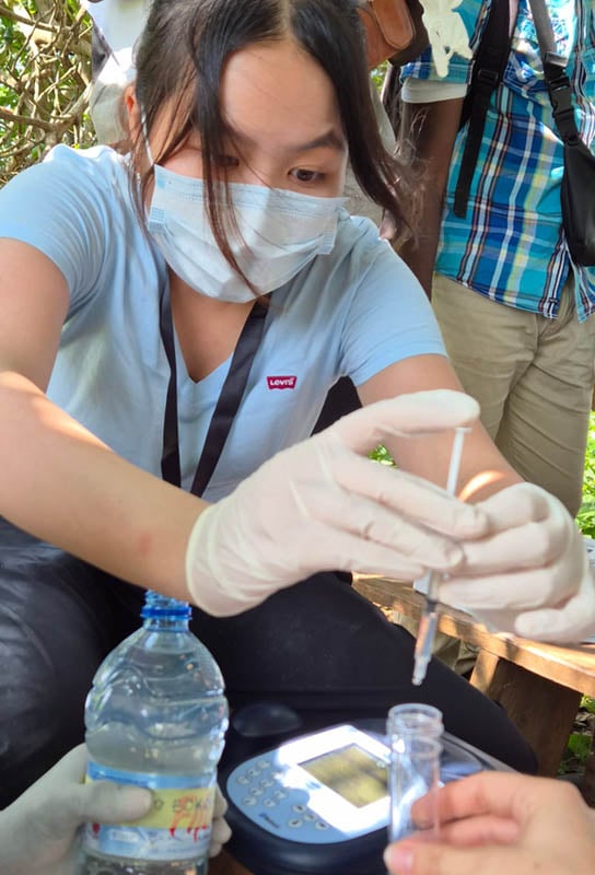 One of the team uses an eyedropper to put water into a vial that will be tested for bacteria and waterborne diseases