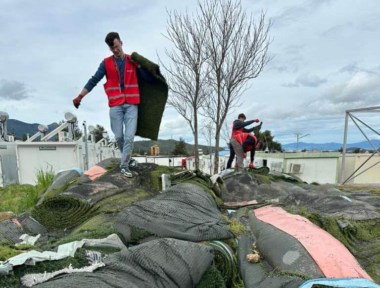Short-term volunteer missionaries from Reach Beyond and Eurorelief work together to repurpose discarded rolls of artificial turf for a camp of refugee residents.