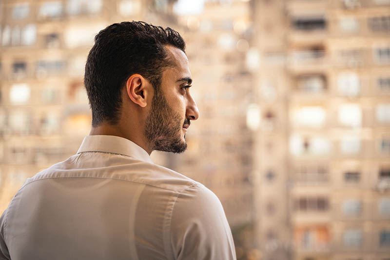 profile of Man looking out at tall neighboring apartment buildings