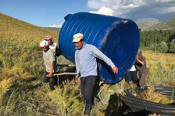 Men carrying a water tank for a potable water project