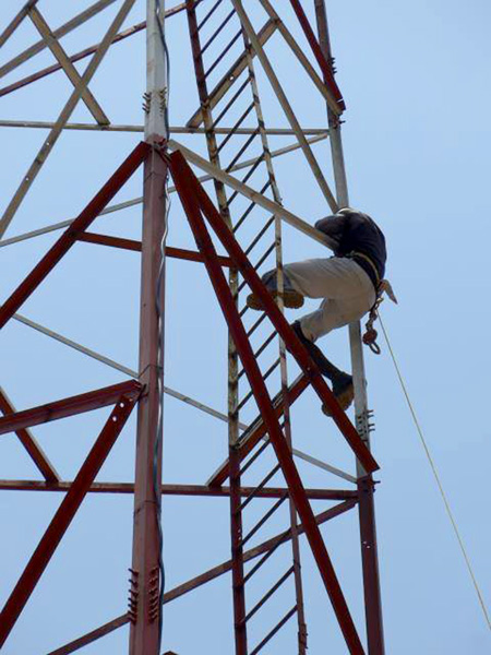A Congolese worker climbs the tall tower.