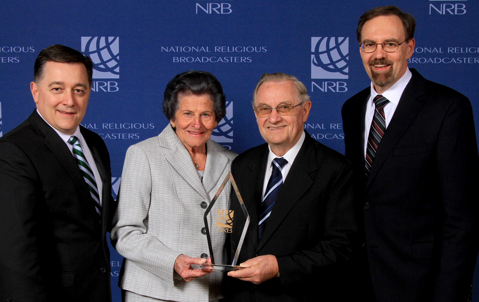 Portuguese radio program producers Victor and Helena Arndt receive a 50-year Milestone Award from NRB President Jerry Johnson (left) and Bill Blount, chairman of the NRB executive committee.